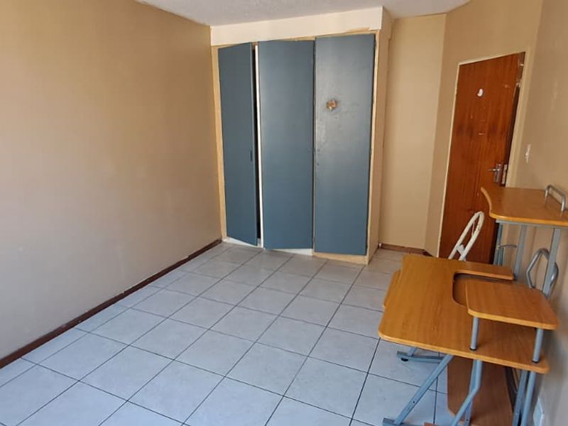 A bedroom featuring tiled flooring and built-in cupboards, requiring cosmetic updates to improve its overall appeal and condition.