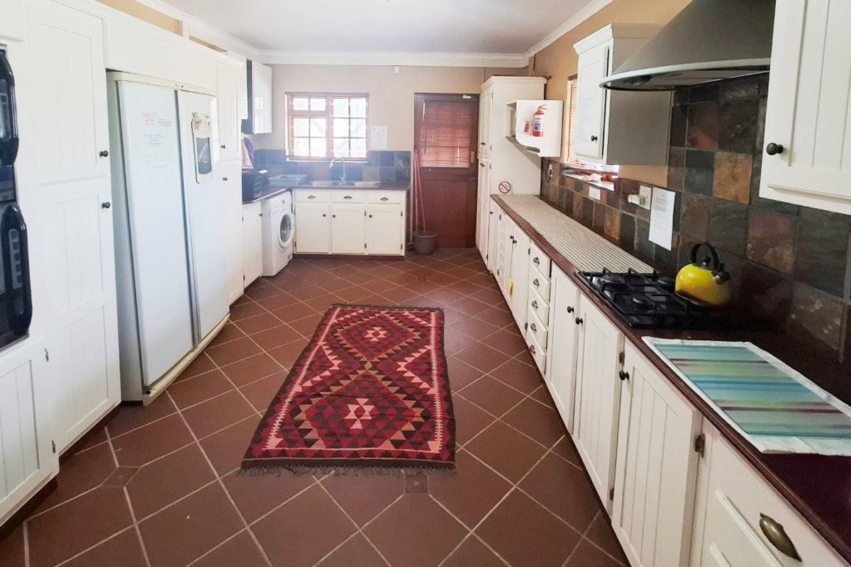Spacious galley-style kitchen featuring white cabinetry, dark countertops, tiled backsplash, built-in oven, gas hob, and integrated laundry area.