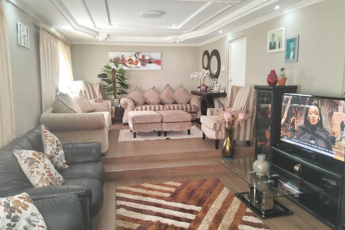 A spacious living room featuring a sunken floor design, decorative tray ceiling with recessed lighting, and tiled flooring.