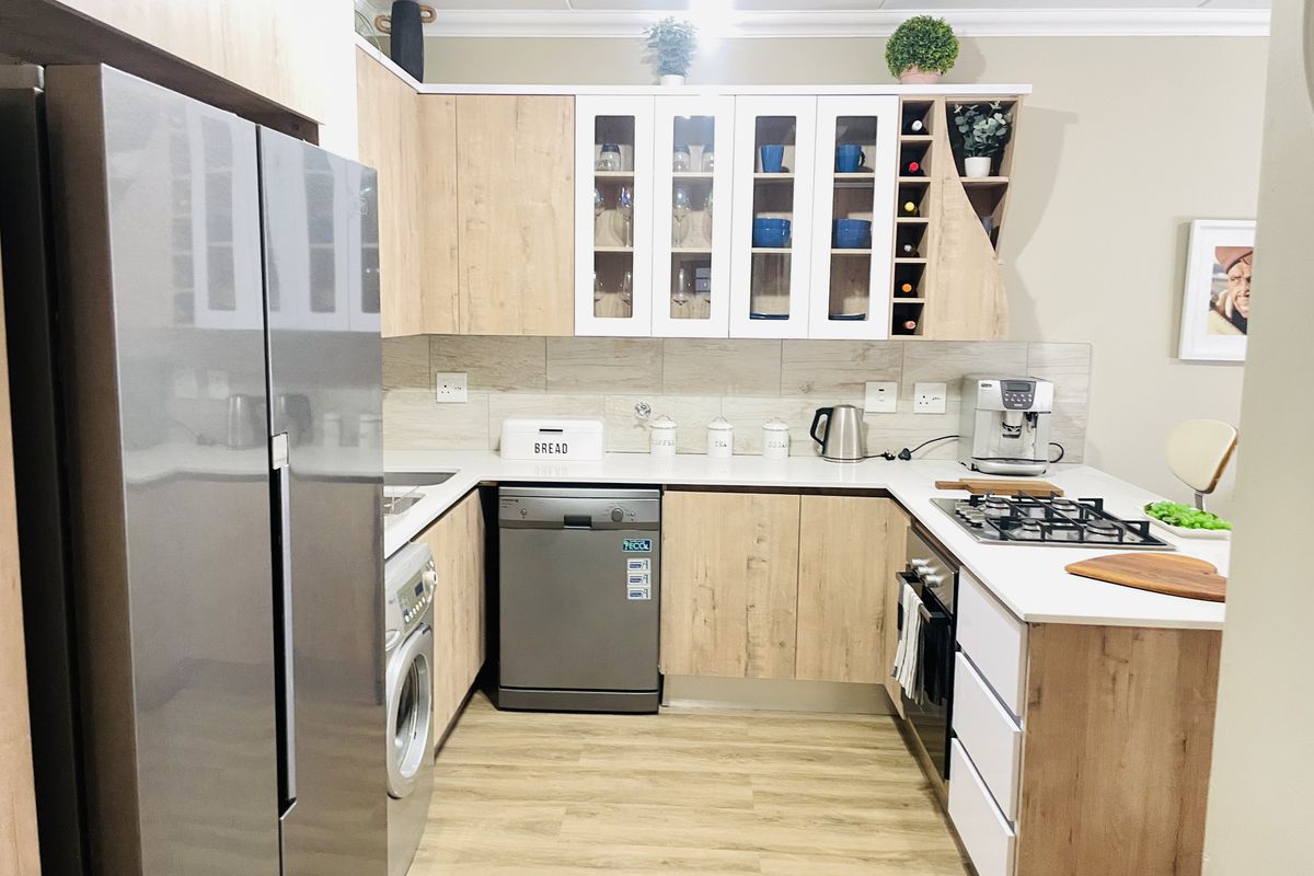 Modern kitchen featuring light wood-tone cabinetry, white countertops, a gas hob, built-in oven, and integrated storage with a dedicated wine rack.