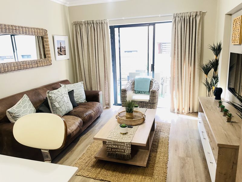 A well-maintained living room featuring laminate flooring and a large sliding glass door that provides access to an outdoor area.