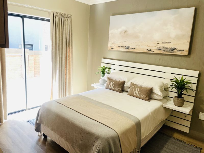 A well-maintained bedroom featuring laminate flooring and a sliding glass door providing access to the exterior.