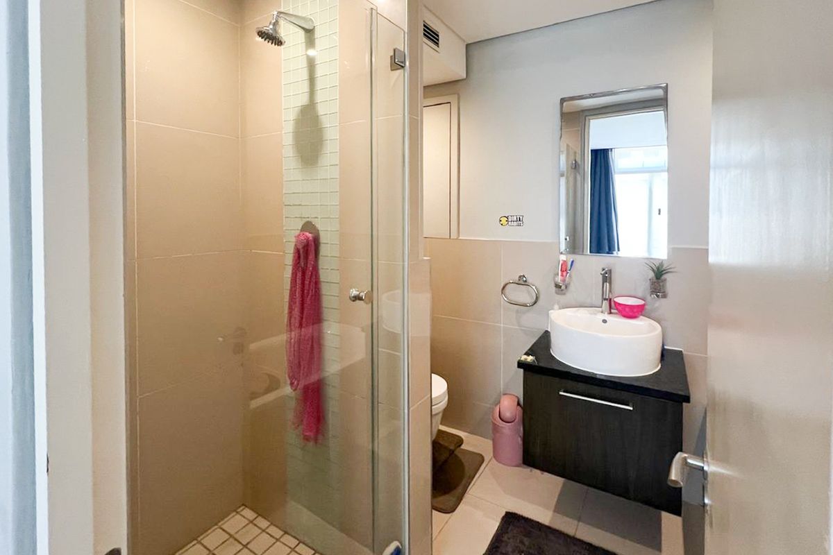 Modern bathroom featuring a glass-enclosed shower with mosaic tile accents, a floating vanity with a vessel sink, and neutral wall tiling.