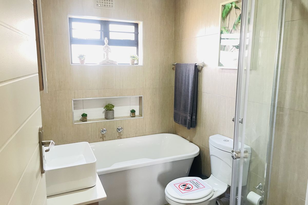 Modern bathroom featuring a freestanding bathtub, vessel sink, glass-enclosed shower, and a convenient built-in wall niche for storage.