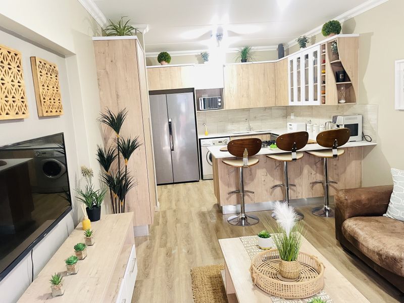 Modern open-plan living area featuring a well-appointed kitchen with light wood cabinetry, breakfast bar, and seamless flow into the lounge space.