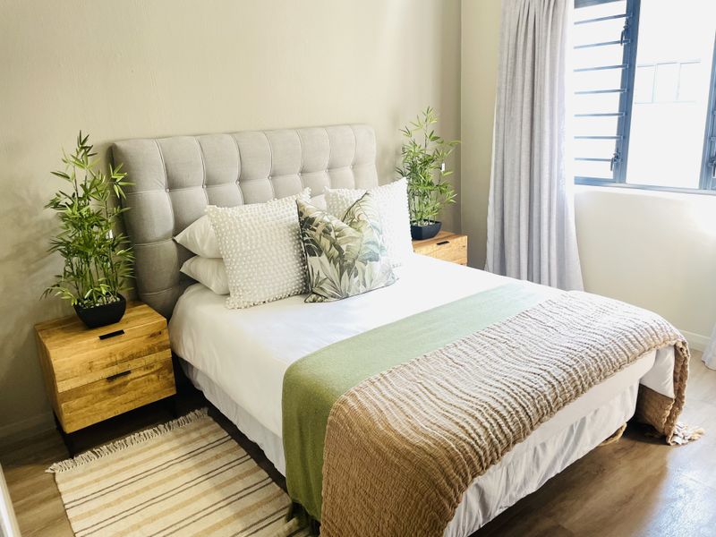 A well-maintained bedroom featuring modern laminate flooring and a functional louvre window, providing a bright and comfortable living space.