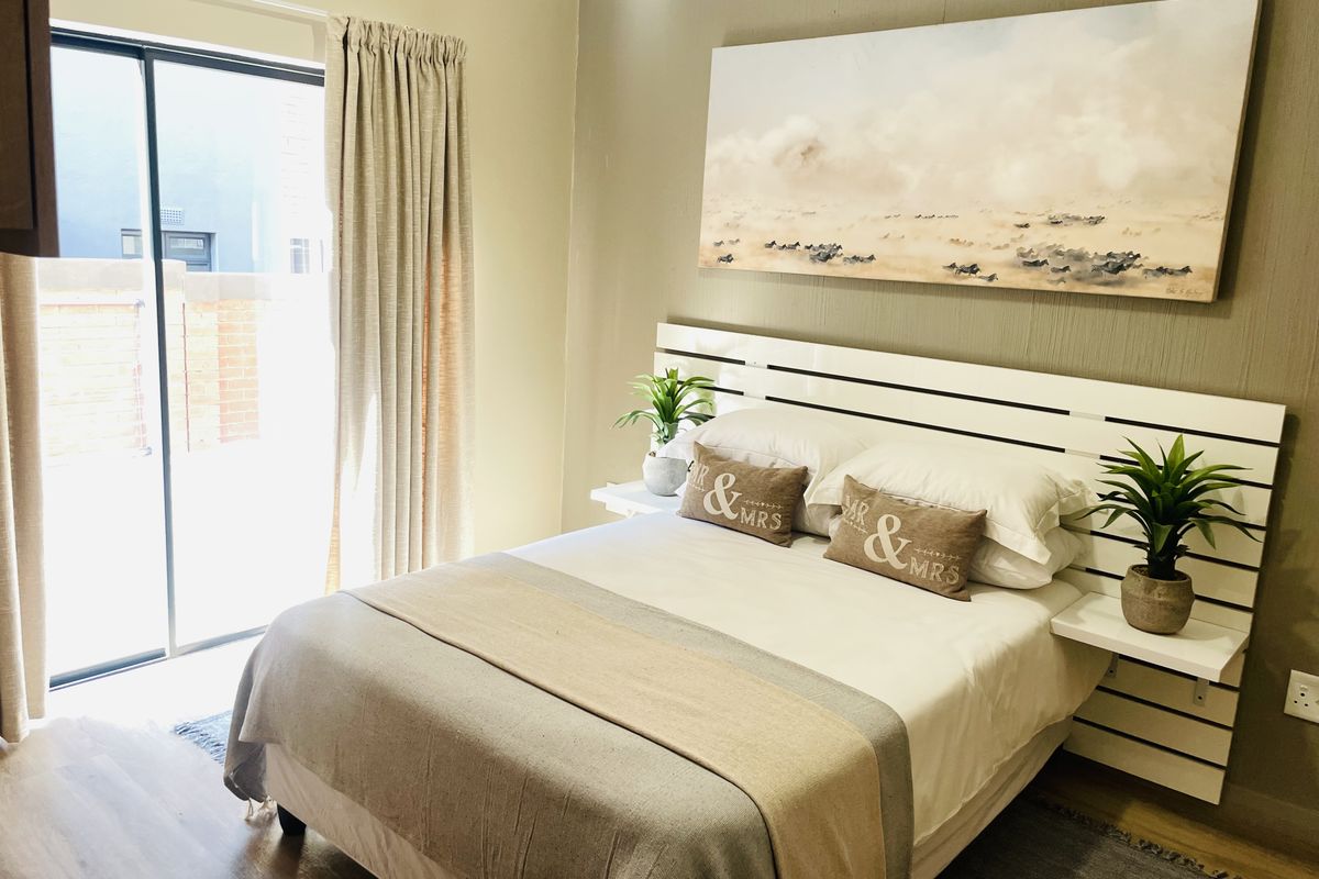 A well-maintained bedroom featuring laminate flooring and a sliding glass door providing access to the exterior.