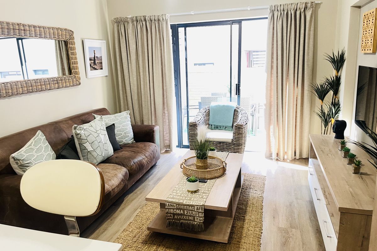 A well-maintained living room featuring laminate flooring and a large sliding glass door that provides access to an outdoor area.