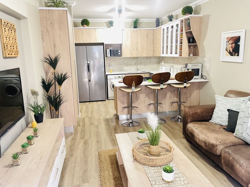 Modern open-plan living area featuring a well-appointed kitchen with light wood cabinetry, breakfast bar, and seamless flow into the comfortable lounge space.