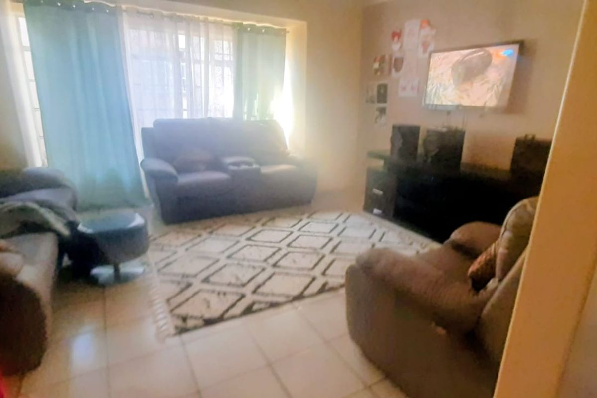 A comfortable living room featuring tiled flooring and large windows that allow for natural light, creating a bright and inviting space.