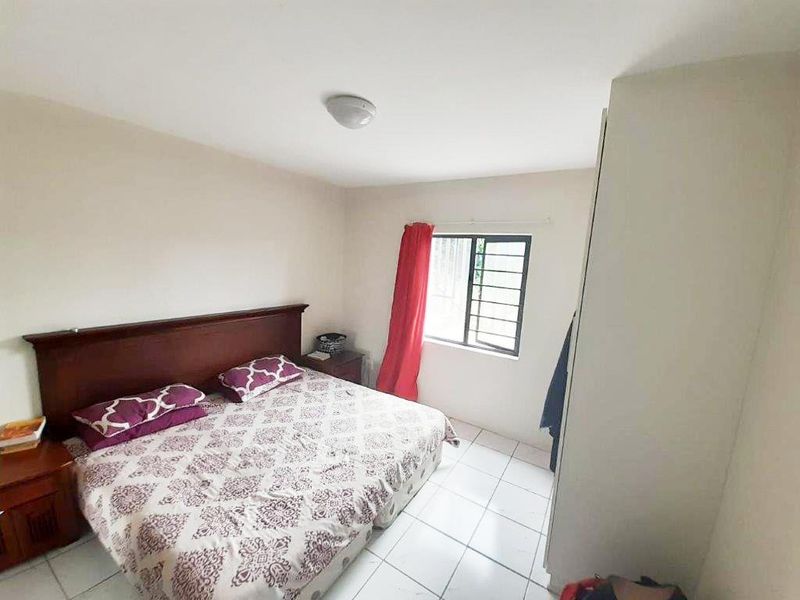 A functional bedroom featuring tiled flooring, a built-in wardrobe, and a window allowing natural light.