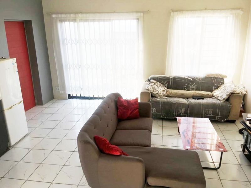 A living room area featuring tiled flooring and a sliding glass door with a security gate, providing access to the exterior.