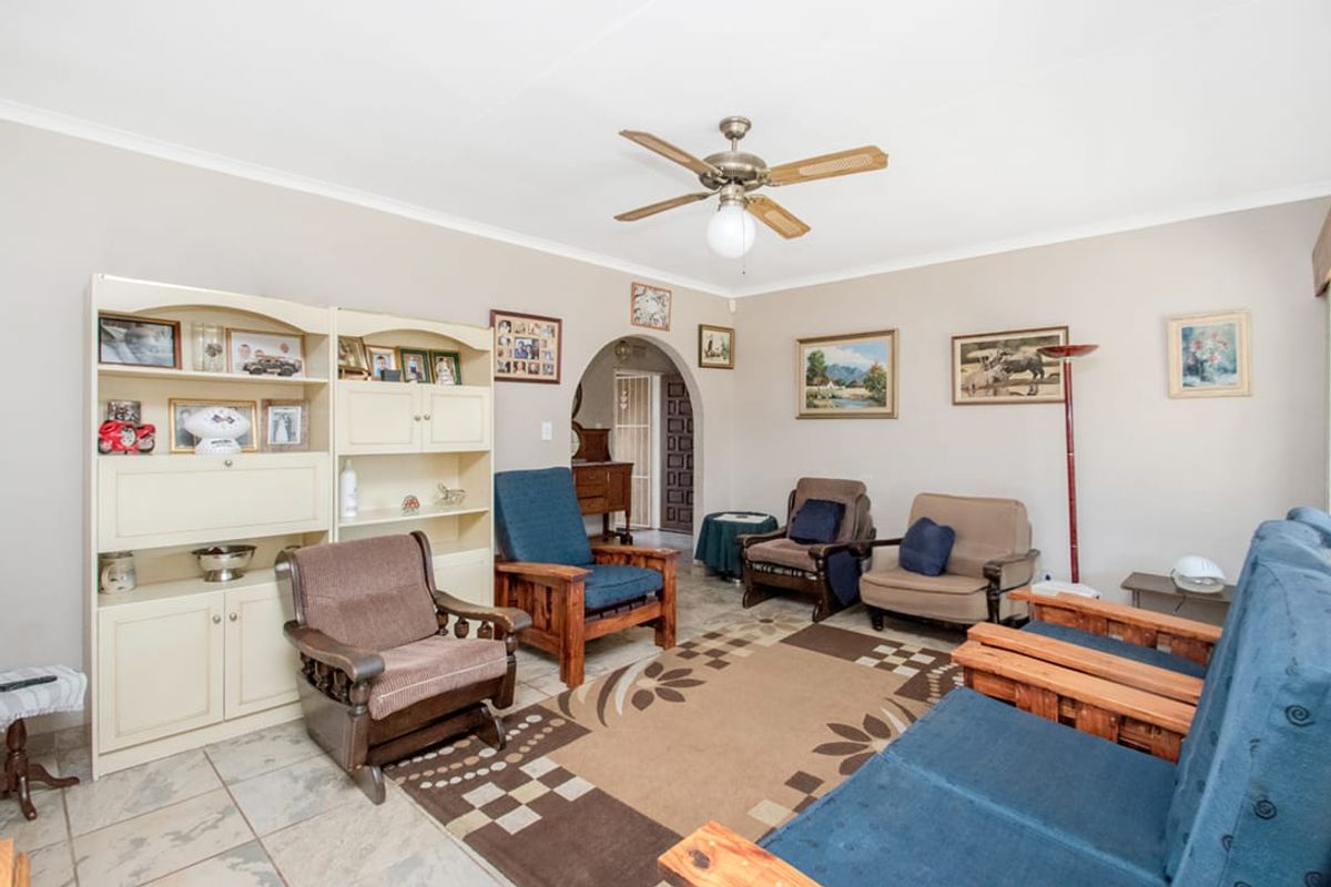A living room featuring tiled flooring, a ceiling fan, and an arched doorway leading to an adjacent space.