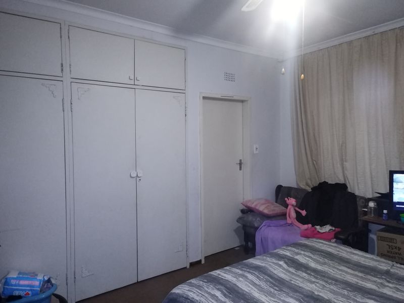 A bedroom featuring built-in cupboards with overhead storage and a ceiling fan.