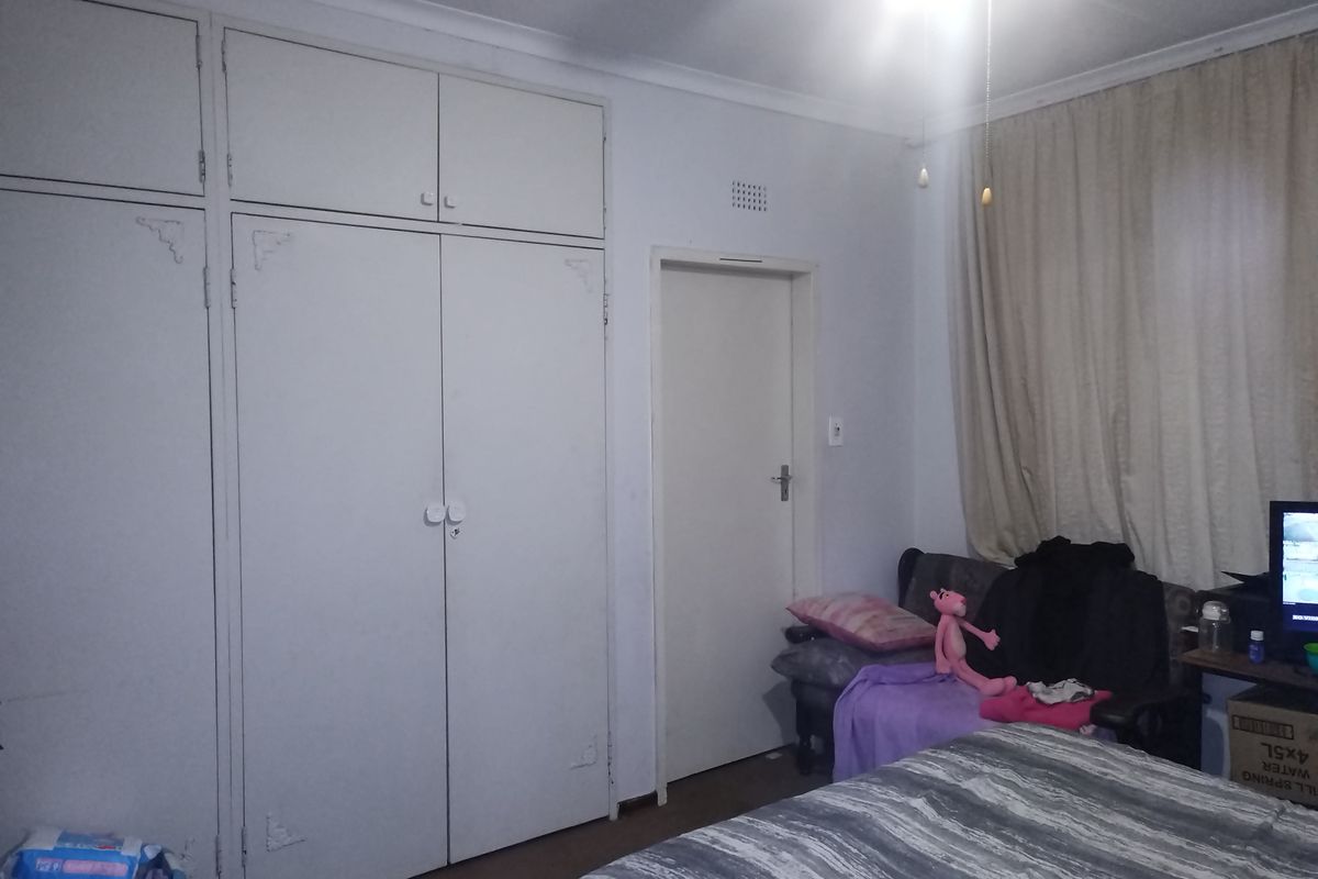 A bedroom featuring built-in cupboards with overhead storage and a ceiling fan.
