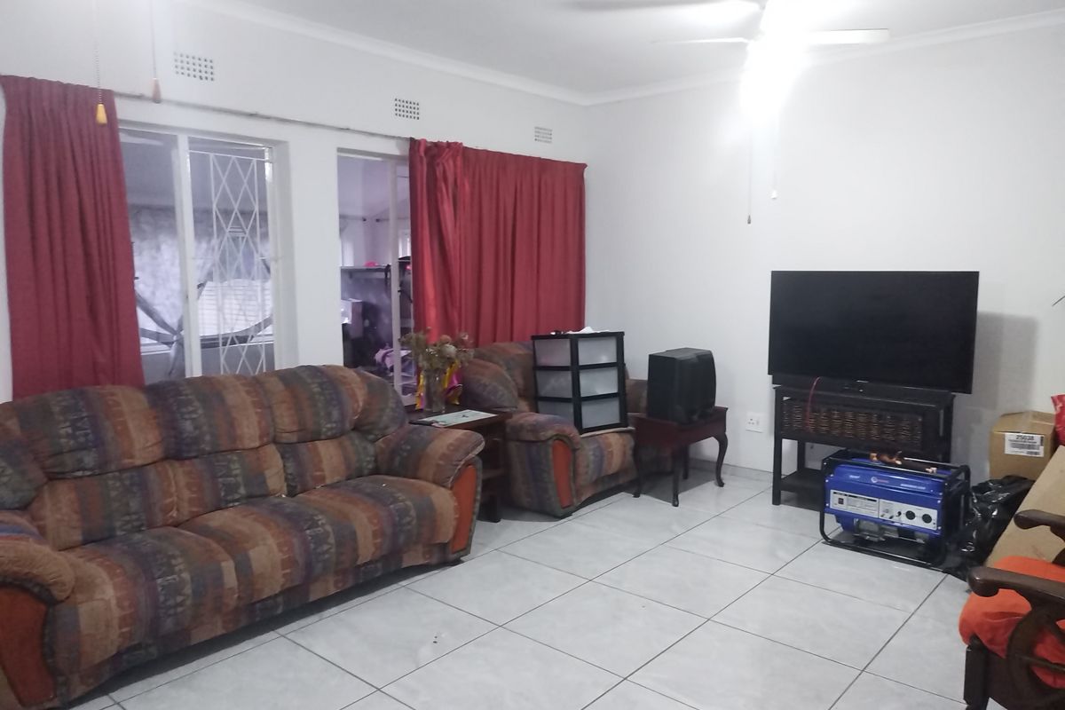 A living room featuring ceramic floor tiles, a ceiling fan, and a sliding door with security gate access.