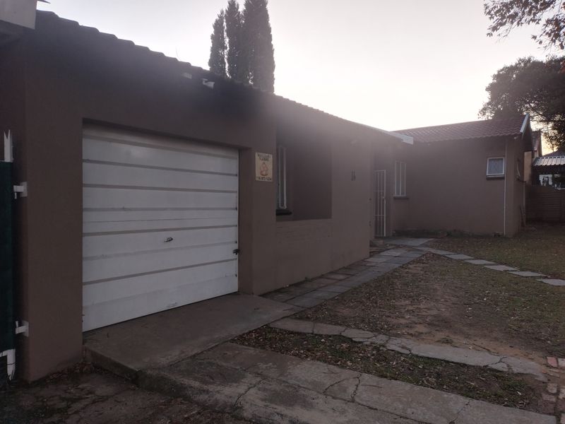 Front exterior view of the property featuring a single garage, paved walkway, and tiled roof structure.