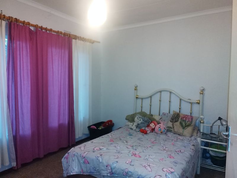 A standard bedroom featuring neutral walls, cove cornicing, and a window with a fitted curtain rod.