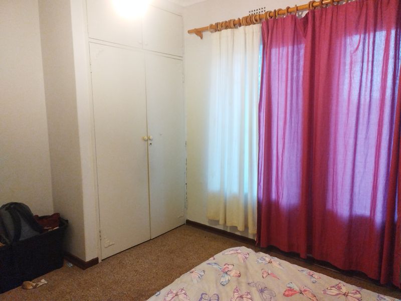 A bedroom featuring a built-in wardrobe and carpet flooring, requiring cosmetic updates to improve its overall appeal.