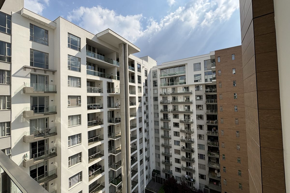 A high-angle view of a modern apartment complex featuring multiple levels of balconies and contemporary architectural facade finishes.