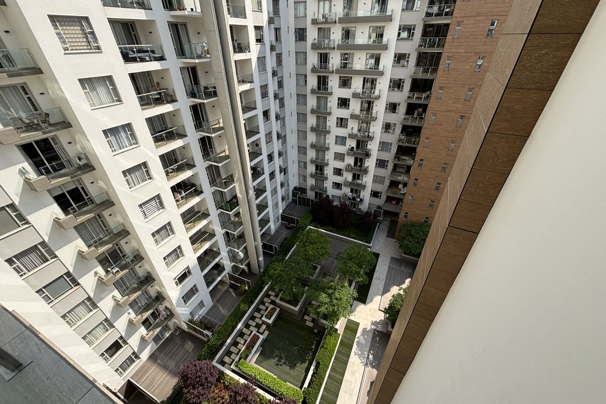High-angle view of a modern apartment complex courtyard featuring landscaped gardens, paved walkways, and multiple residential balconies.