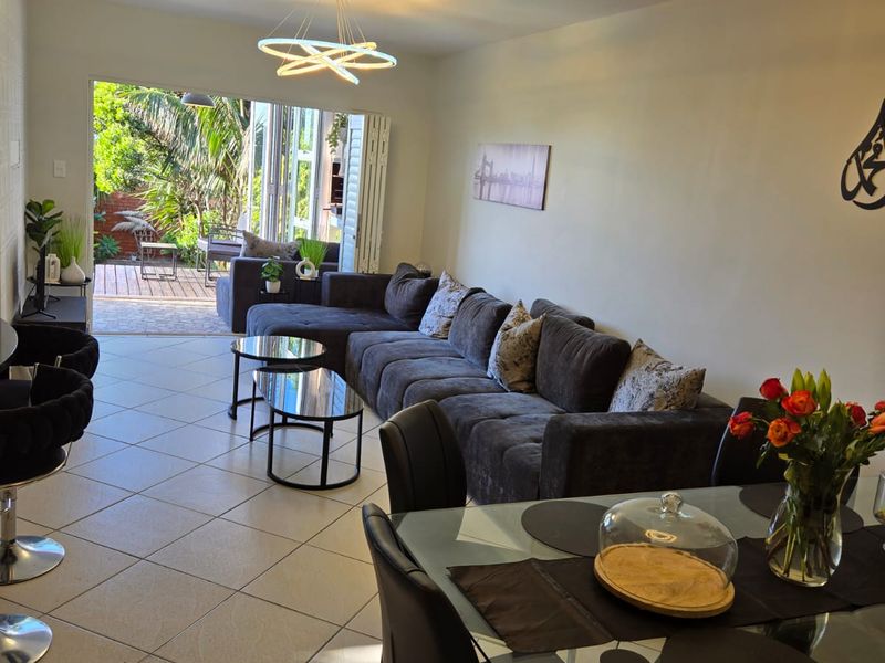 Spacious open-plan living and dining area featuring ceramic floor tiles, modern pendant lighting, and seamless access to the outdoor patio through bi-fold doors.