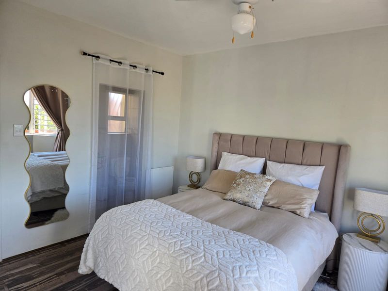 A well-maintained bedroom featuring laminate flooring, a ceiling fan, and neutral wall finishes, providing a comfortable and functional living space.