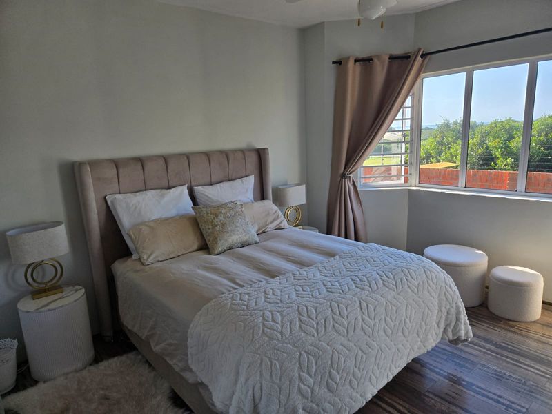 A well-lit bedroom featuring a large window with natural light and a ceiling fan, offering a comfortable and inviting living space.