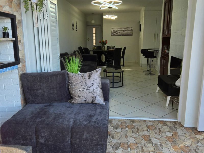 An open-plan living and dining area featuring stone-clad accents, tiled flooring, and seamless transition to an outdoor patio space through bi-fold doors.