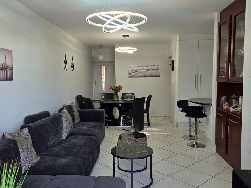 An open-plan living and dining area featuring tiled flooring, modern pendant lighting, and built-in cabinetry, creating a functional and cohesive living space.