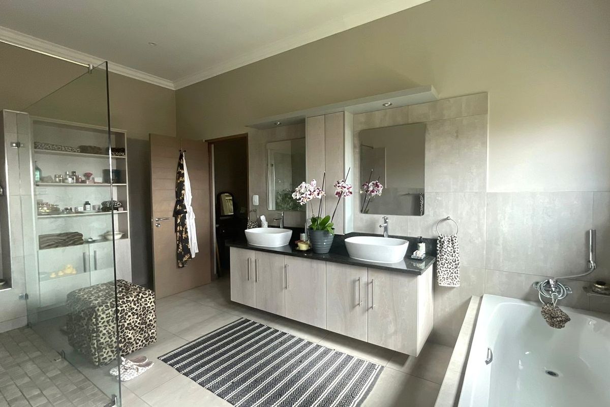 Spacious modern bathroom featuring a double vanity with vessel sinks, a large glass-enclosed shower, and a separate bathtub with neutral tile finishes.