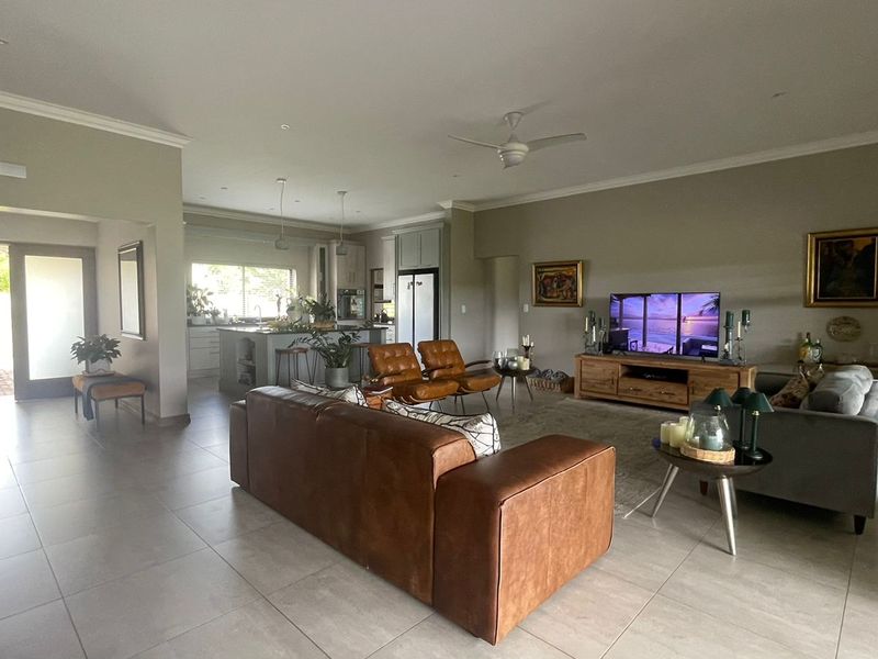 Spacious open-plan living area featuring tiled floors, recessed lighting, a ceiling fan, and a modern kitchen with a central island.