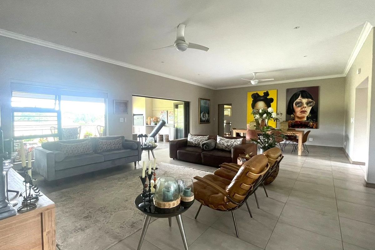 Spacious open-plan living and dining area featuring tiled floors, ceiling fans, and large sliding glass doors that provide access to the outdoor space.
