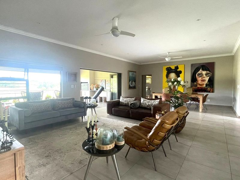 Spacious open-plan living and dining area featuring tiled floors, ceiling fans, and large sliding glass doors that provide access to the outdoor space.