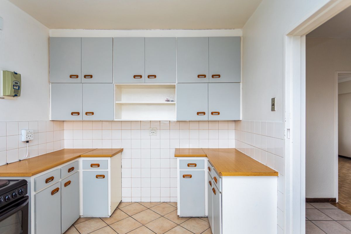 A functional kitchen featuring light blue cabinetry, wood-look laminate countertops, tiled backsplash, and tiled flooring.