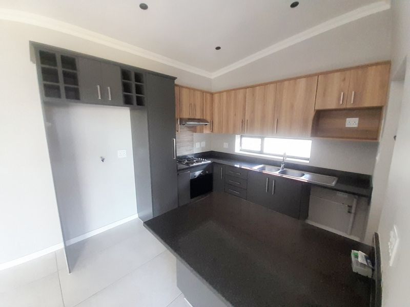 Modern kitchen featuring two-tone cabinetry, granite countertops, built-in oven, gas hob, and a functional breakfast nook layout.