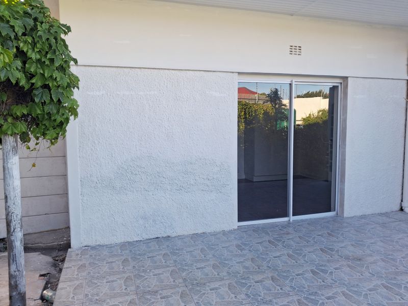 A covered patio area featuring tiled flooring and a sliding glass door entrance to the apartment.