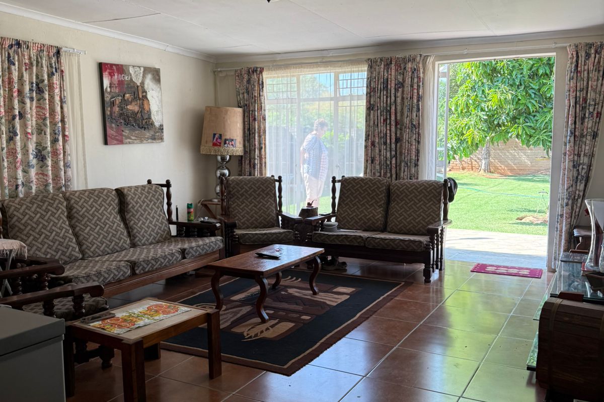 Spacious living room featuring large ceramic floor tiles and direct access to the rear garden through a sliding glass door.