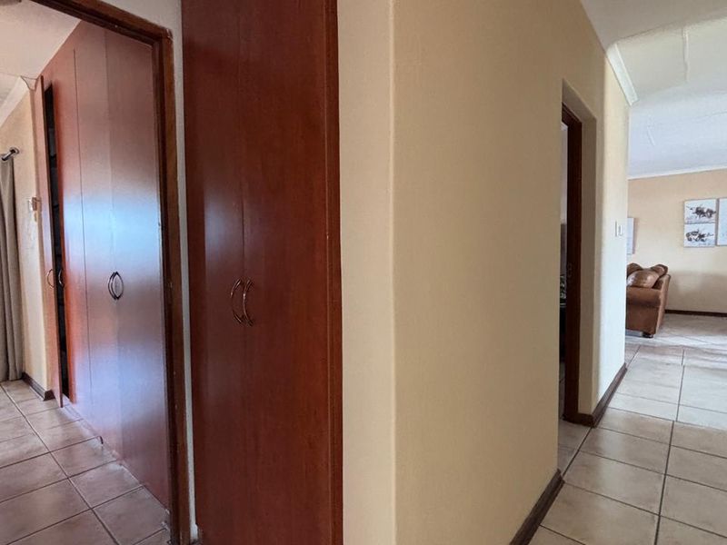 A functional hallway featuring tiled flooring and built-in wooden cupboards, providing access to adjacent living areas.