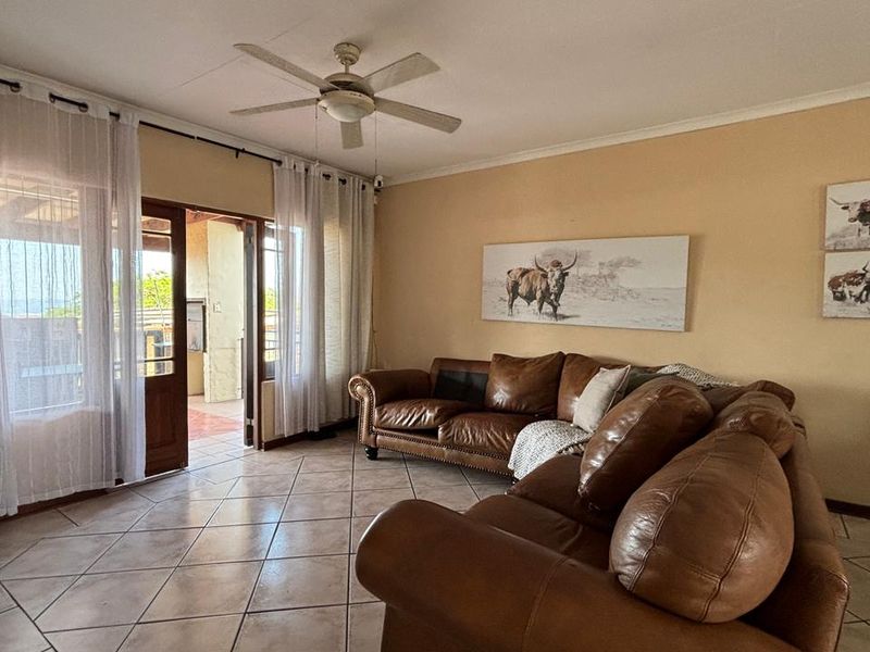 Spacious living room featuring tiled flooring, a ceiling fan, and direct access to an outdoor patio area through sliding glass doors.