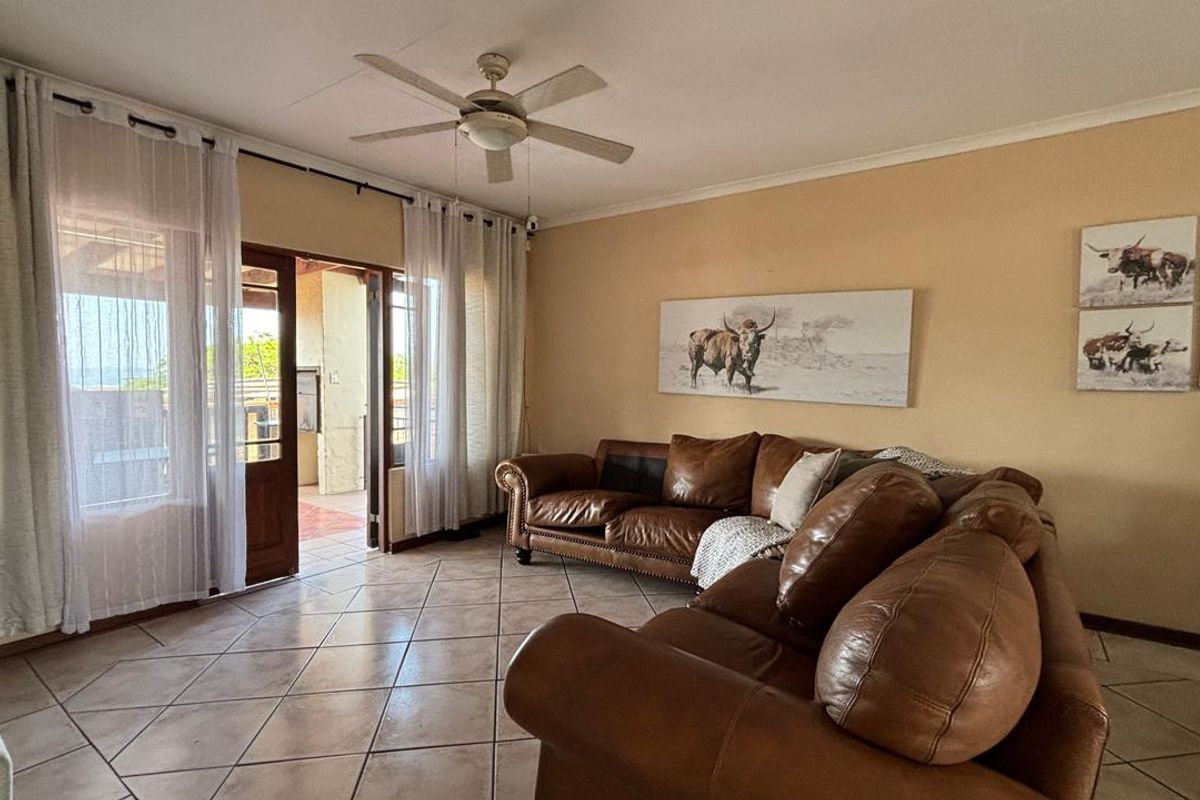 Spacious living room featuring tiled flooring, a ceiling fan, and direct access to an outdoor patio area through sliding glass doors.