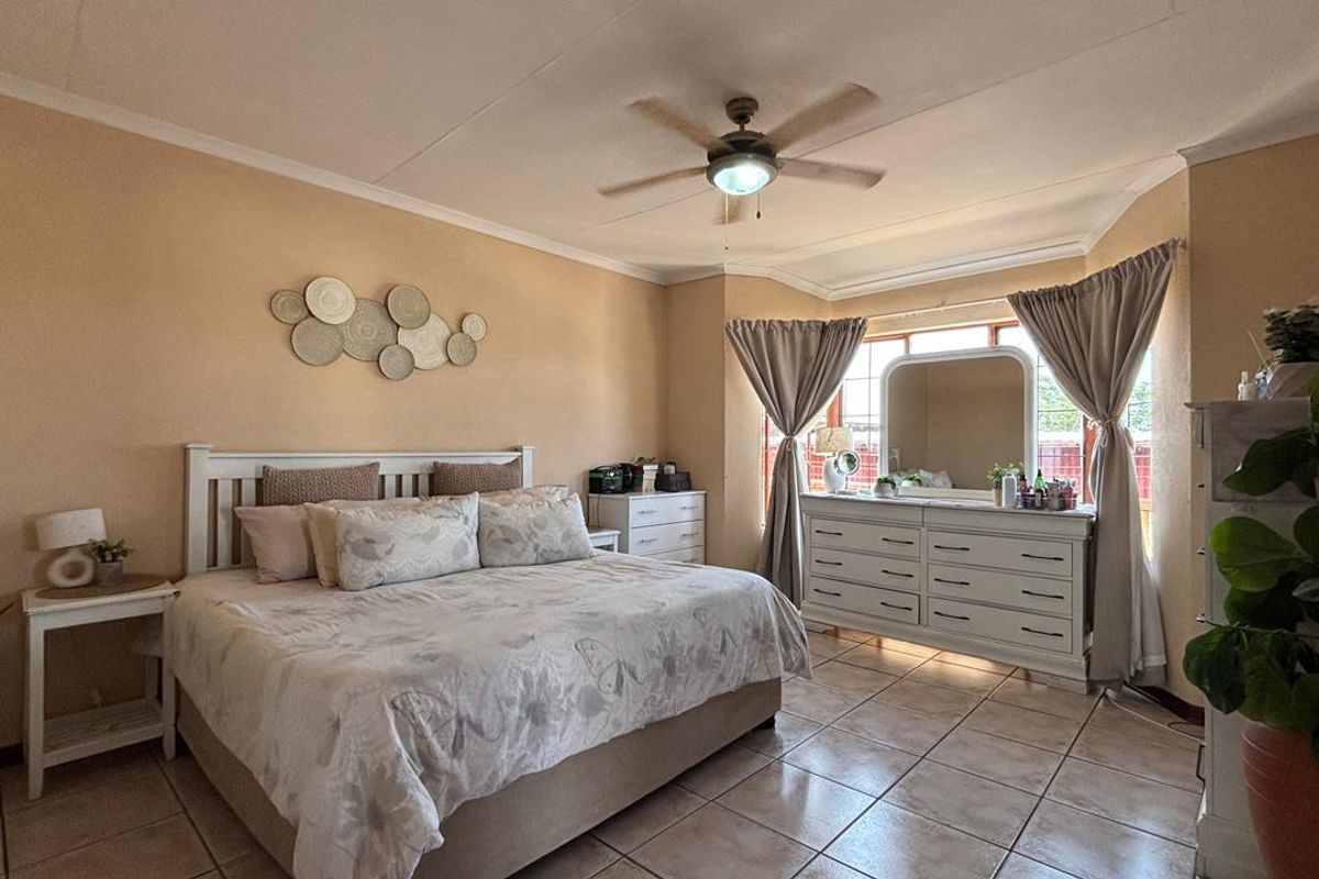 Spacious bedroom featuring tiled flooring, a central ceiling fan, and large windows allowing for natural light.
