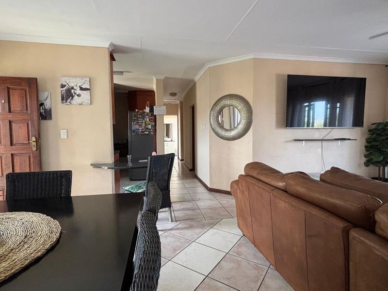 Open-plan living and dining area featuring tiled flooring, coved cornicing, and a ceiling fan, providing a functional and connected layout.
