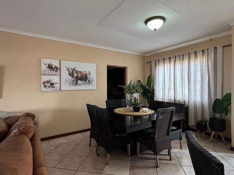 Open plan living and dining area featuring tiled flooring and direct access to the garden through a sliding glass door.