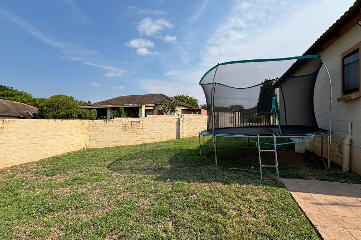 A private rear garden featuring a lawn area, paved walkway, and a perimeter brick boundary wall.