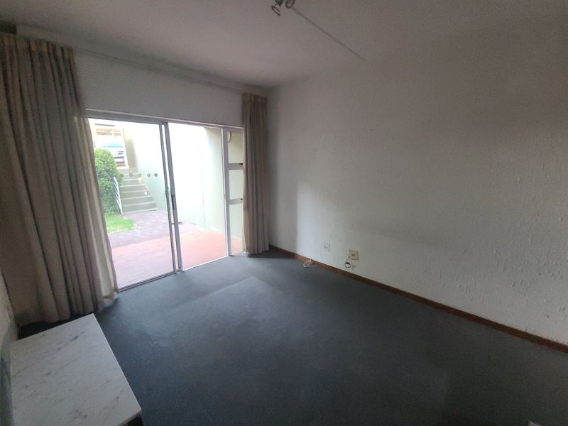 An empty living room featuring carpet flooring and a sliding glass door providing direct access to an outdoor patio area.