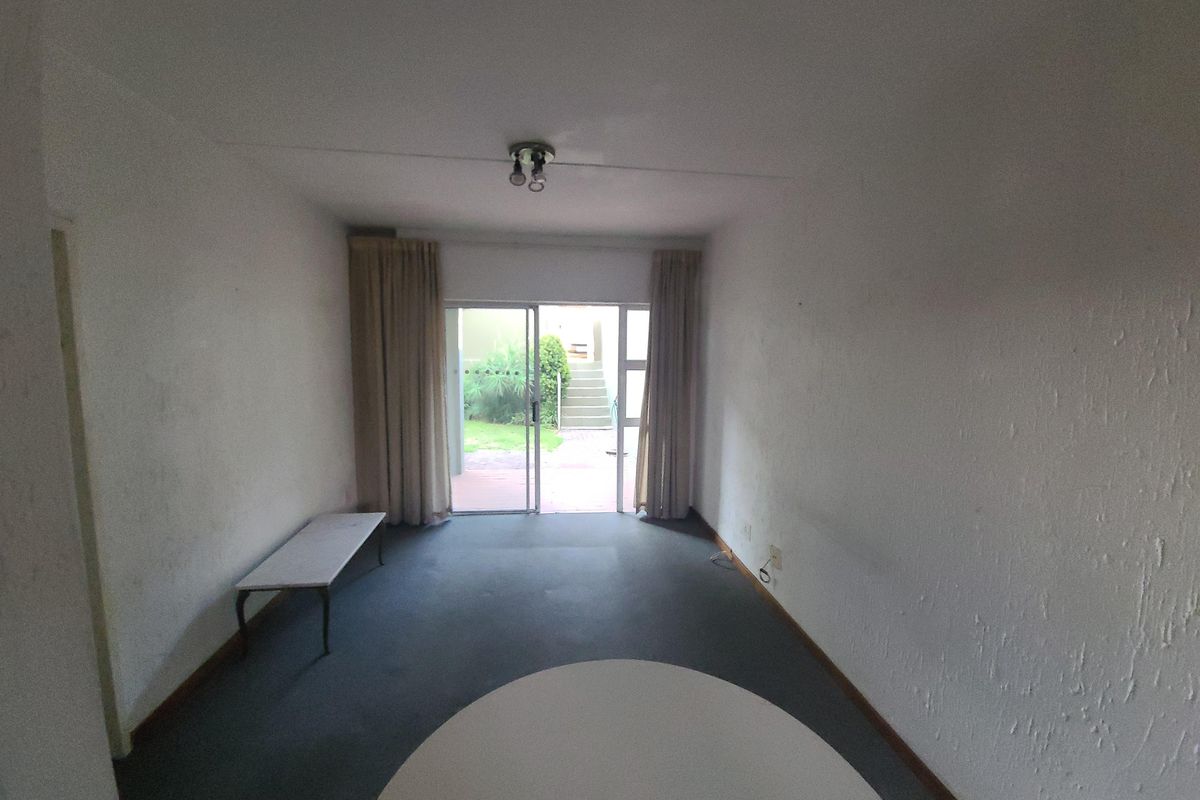 An empty living room featuring a sliding glass door with access to an outdoor area, providing natural light and potential for renovation.