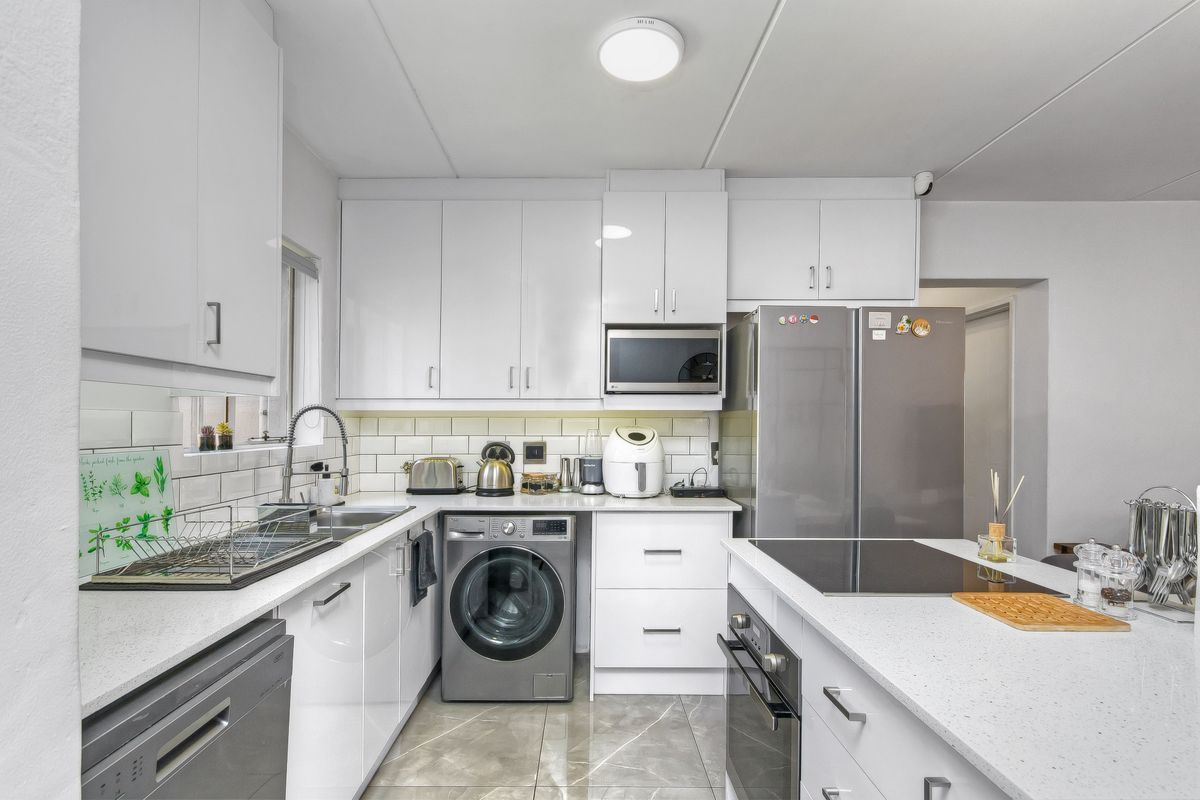 Modern kitchen featuring white cabinetry, stone countertops, subway tile backsplash, integrated oven, hob, and built-in microwave with a functional layout.