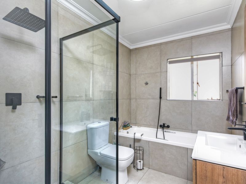 Modern bathroom featuring a glass-enclosed shower, a built-in bathtub, a vanity with a basin, and contemporary matte black fixtures.