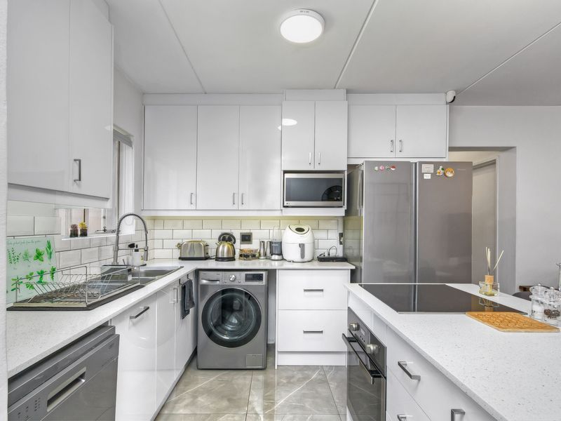 Modern kitchen featuring white cabinetry, stone countertops, subway tile backsplash, integrated oven, hob, and built-in microwave with a functional layout.
